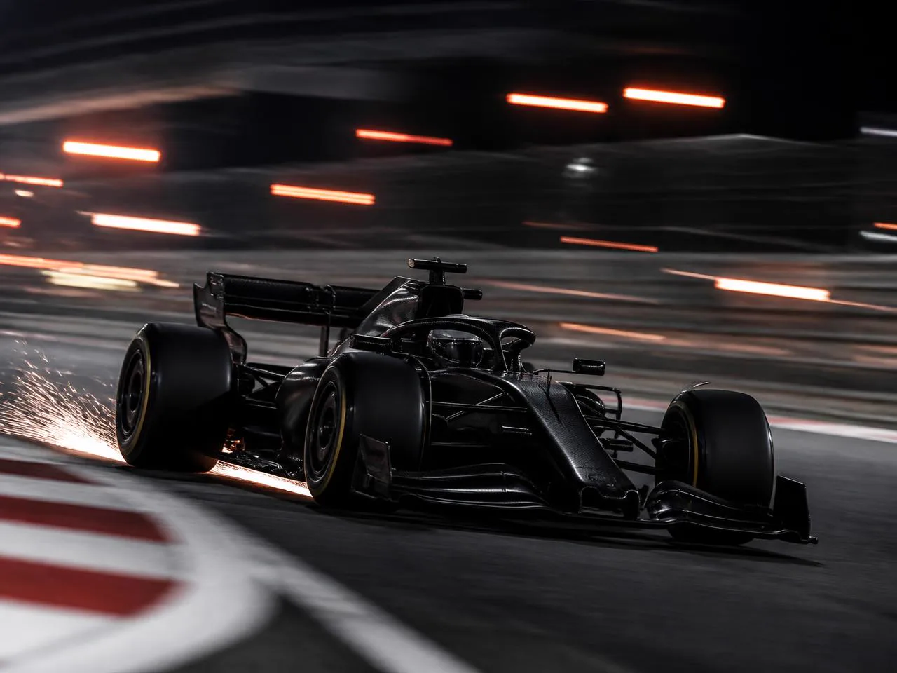 Black Formula-style race car cornering on a night circuit